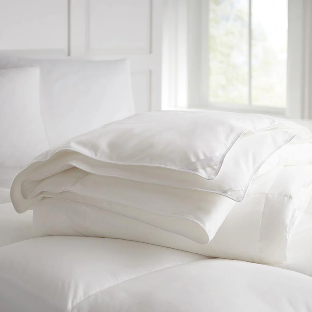 White eucalyptus tencel comforter and pillows on a bed with a neutral background