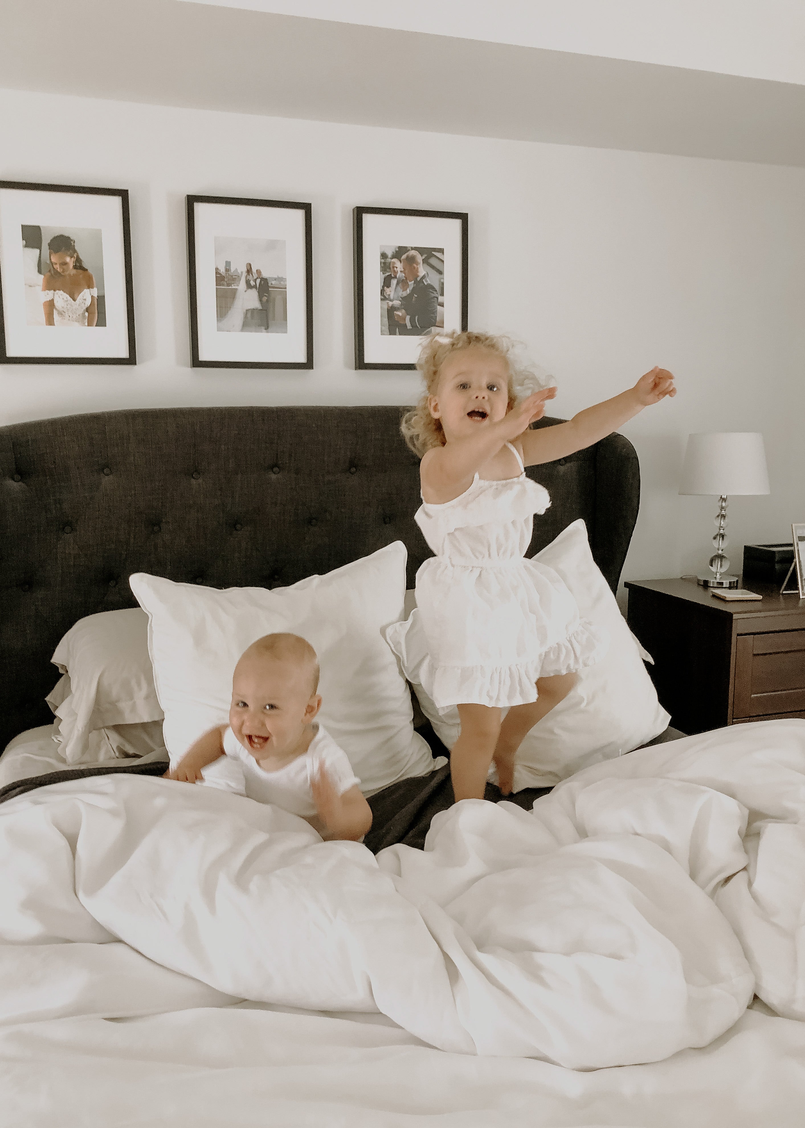 Two children jumping and playing on a bed with soft white eucalyptus sheets and duvet by Eucalypso