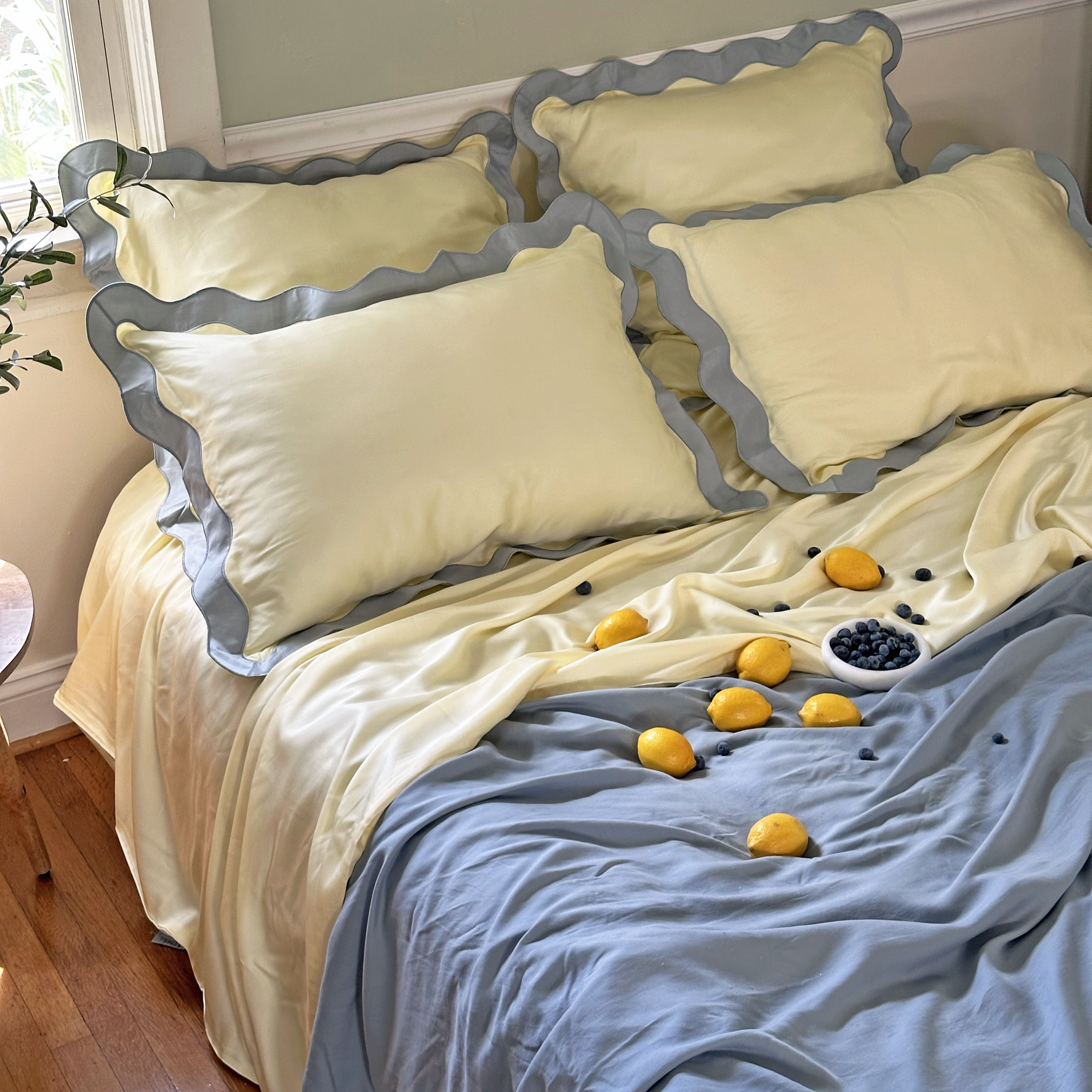 Luxury eucalyptus TENCEL™ lyocell sheets by Eucalypso with blue and yellow scalloped pillowcases and cooling duvet on a styled bed