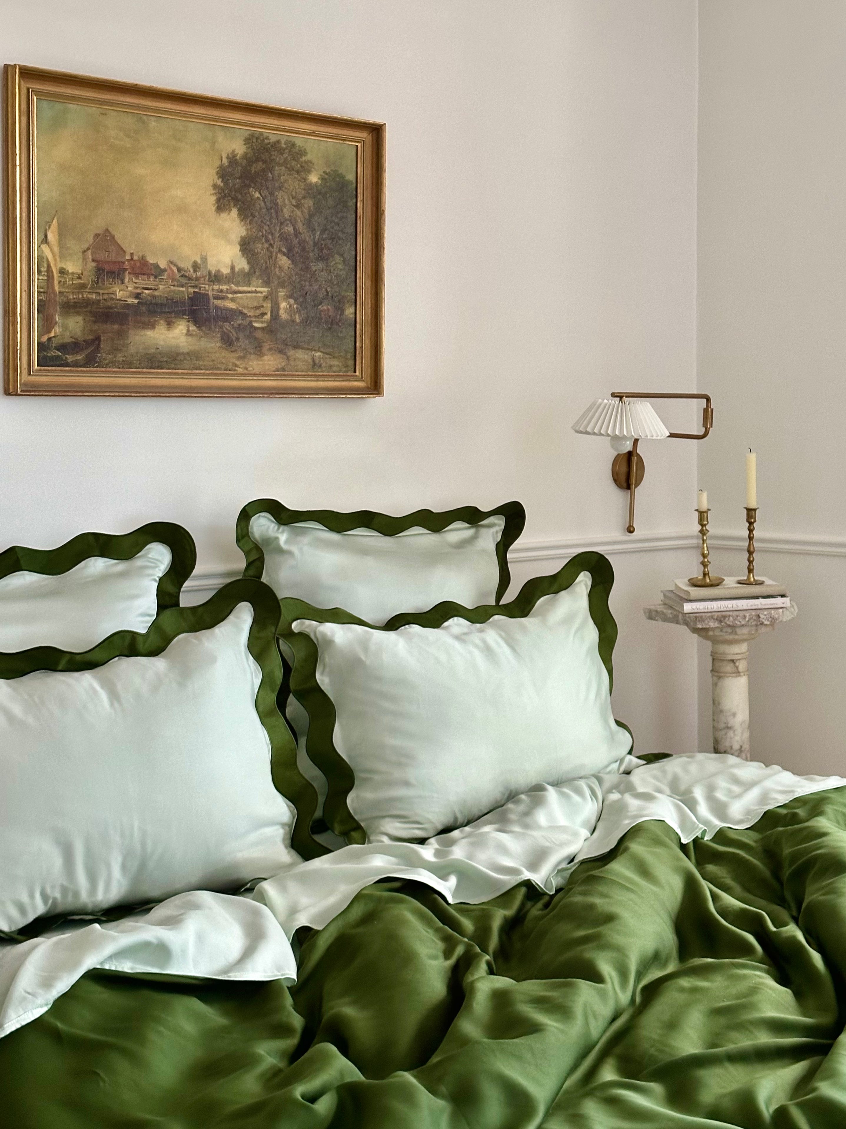 Eucalyptus bedding styled on a bed, featuring smooth, draped fabric and scalloped pillowcases.