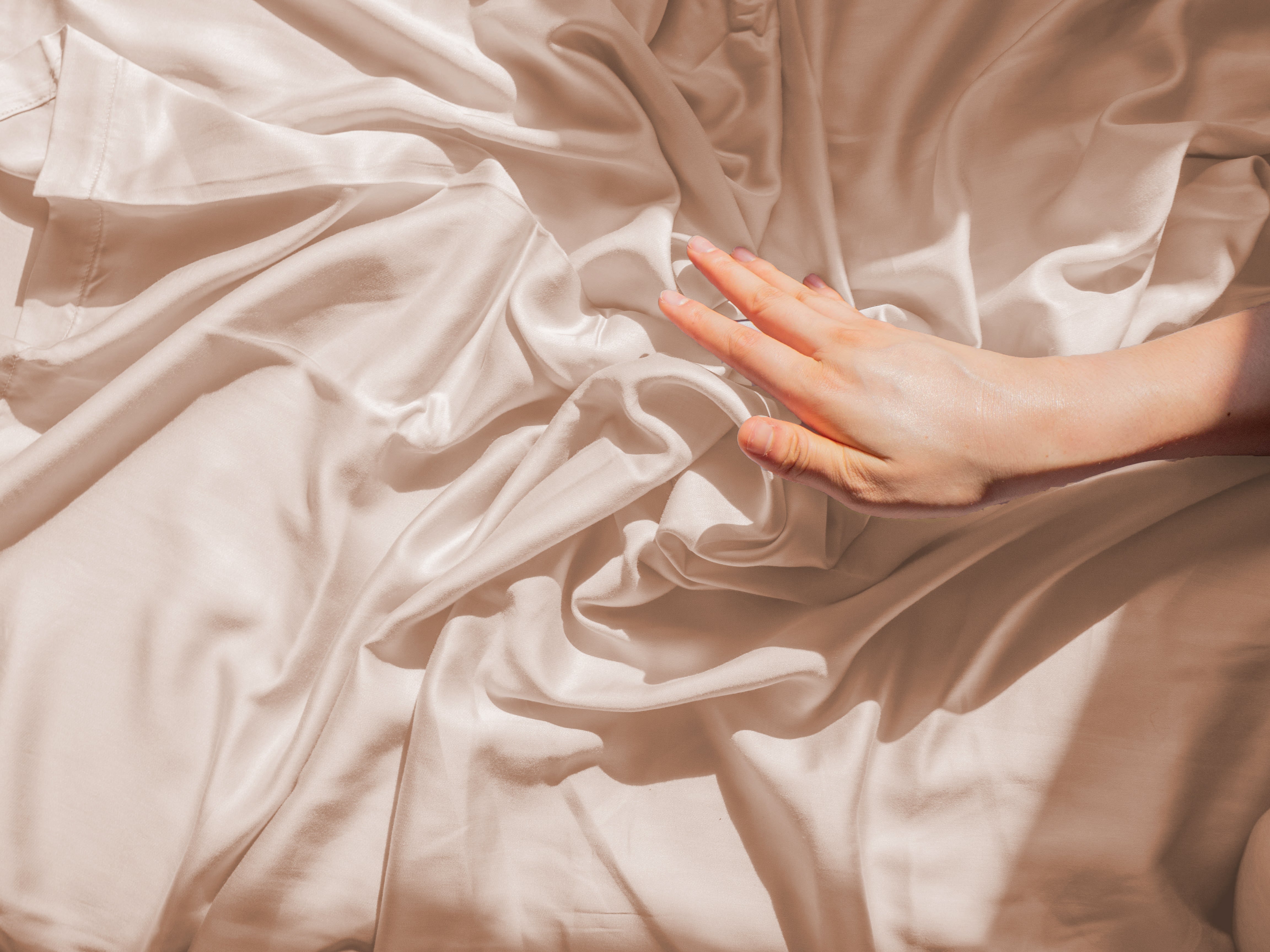 Hand touching soft eucalyptus TENCEL™ lyocell fabric with a smooth, silky drape