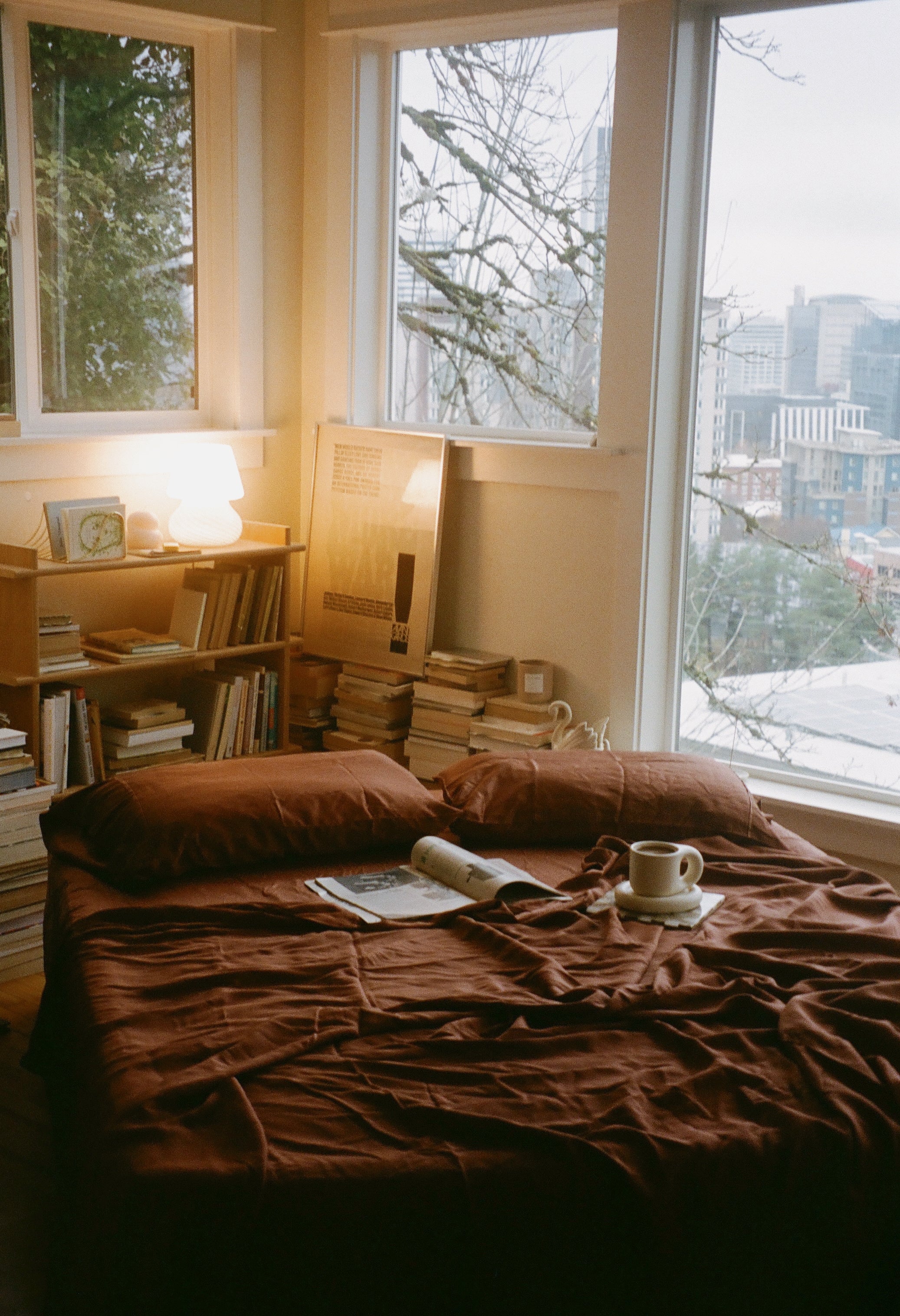Cozy eucalyptus tencel sheets in terracotta brown color in a moody ambient room filled with warm light and books