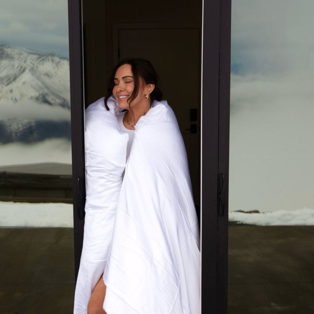 Woman wrapped in white eucalyptus comforter enjoying breathable, temperature-regulating bedding