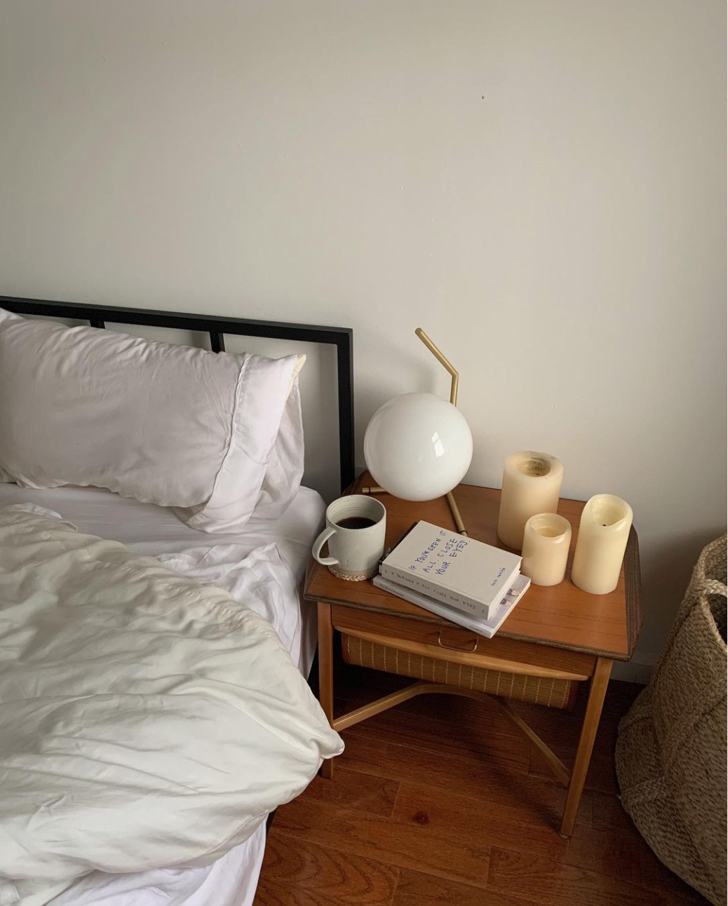 New york style bedroom with cooling eucalyptus sheets in white in bed next to bedside table with a mug and candels