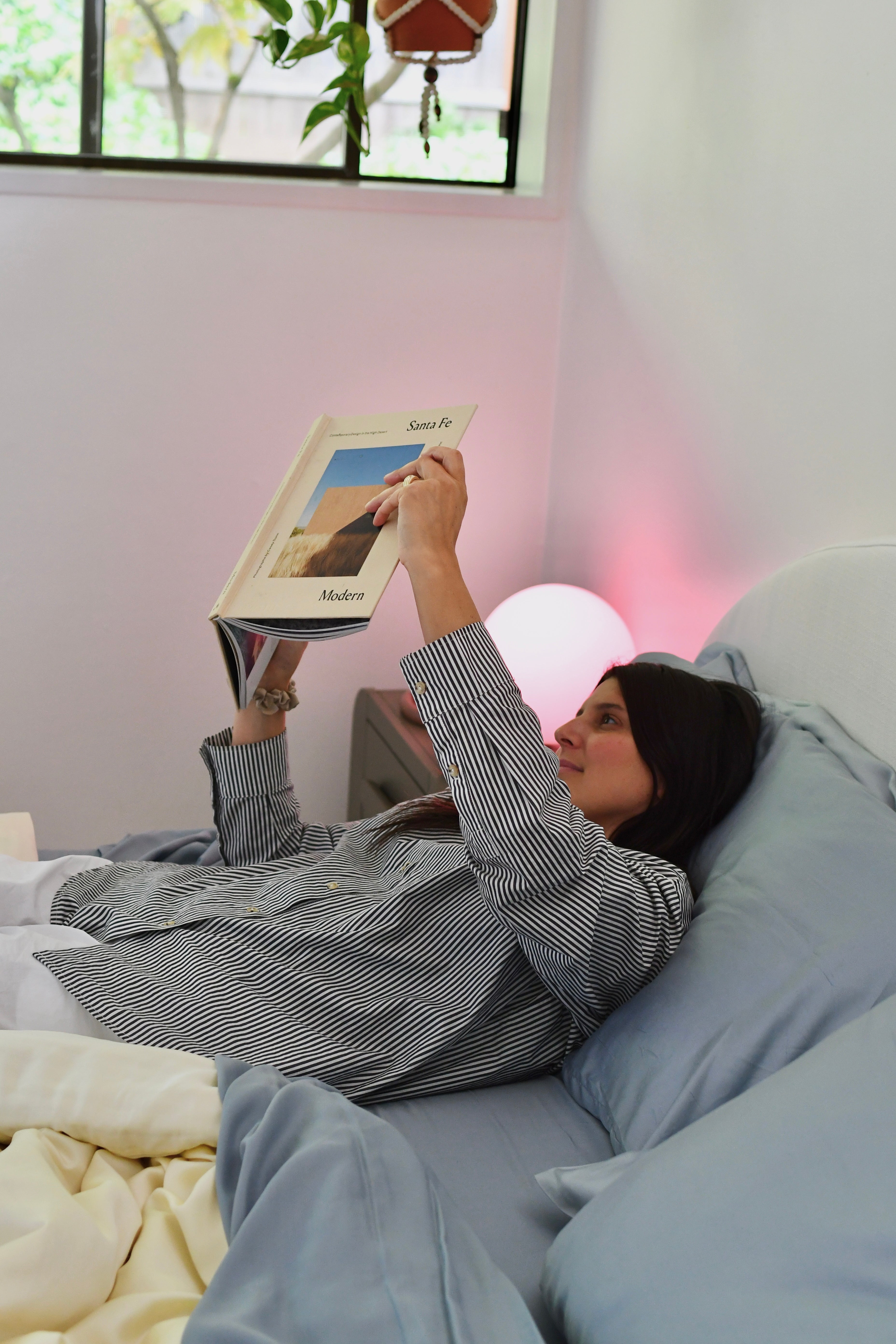 Woman relaxing in bed reading a book on soft, cooling eucalyptus sheets designed for breathable, temperature-regulating sleep.