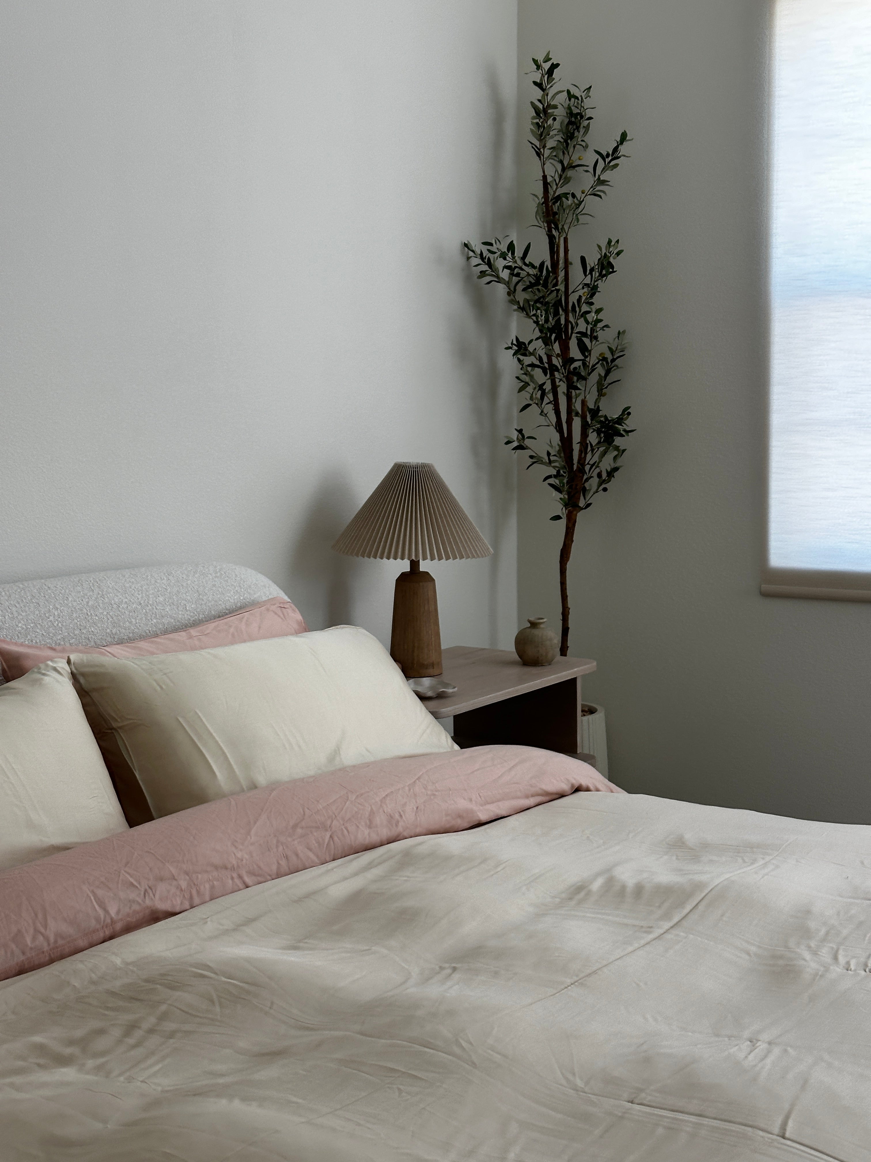 Beautiful soft neutral bedding with eucalyptus sheets in beige and light pink with a softy lit neutral room