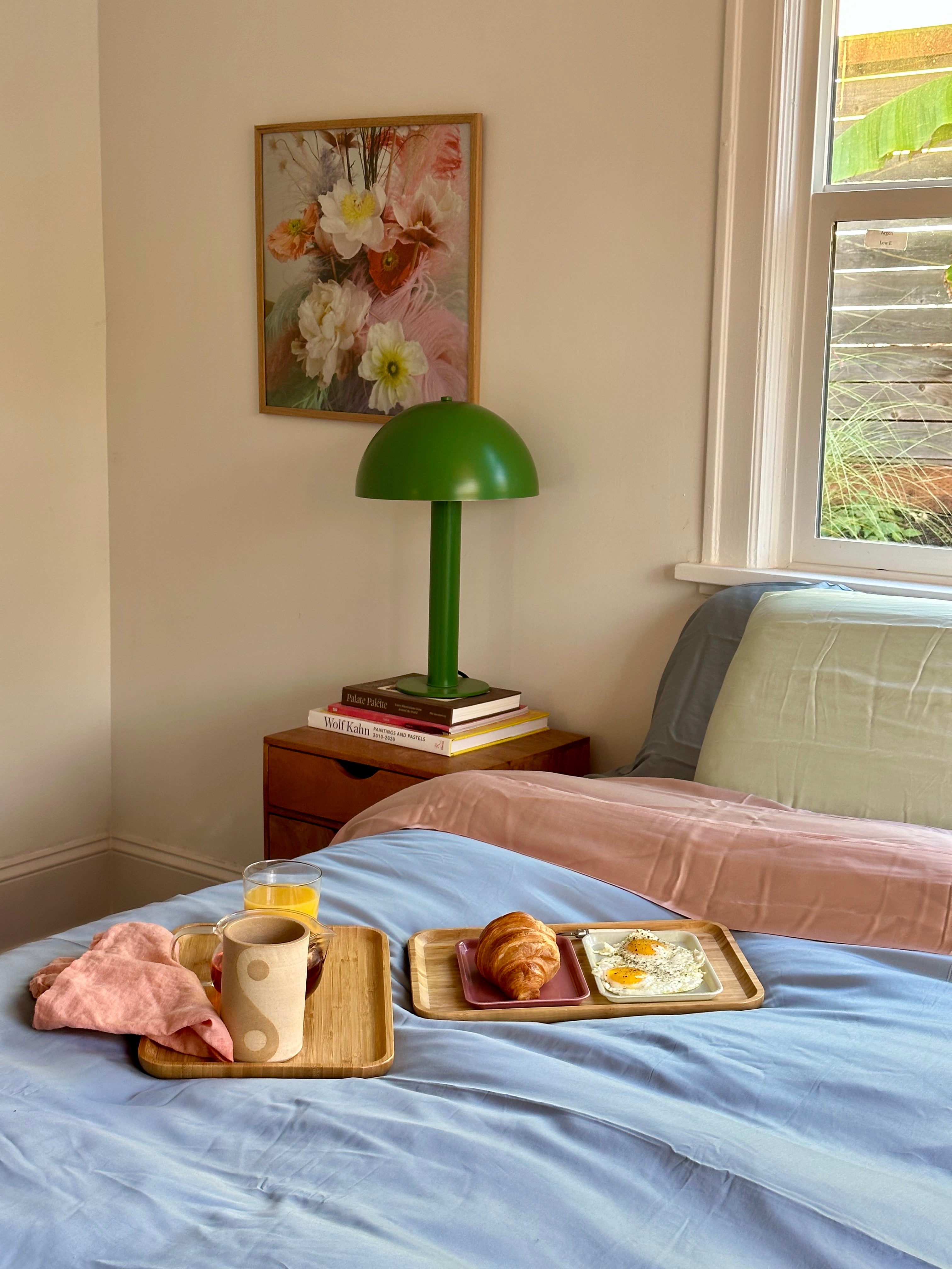 Colorful eucalyptus tencel sheets in light blue, light pink, and light green, styled with breakfast tray in bed. 